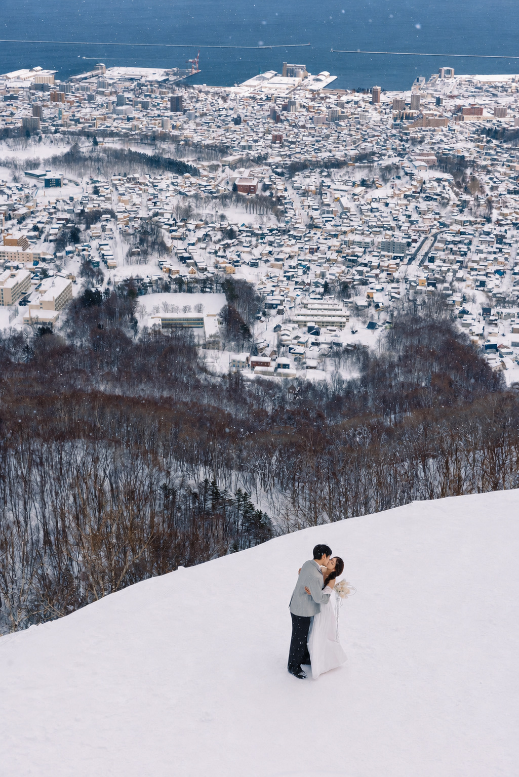 北海道小樽雪坡俯瞰雪城与海的婚纱照