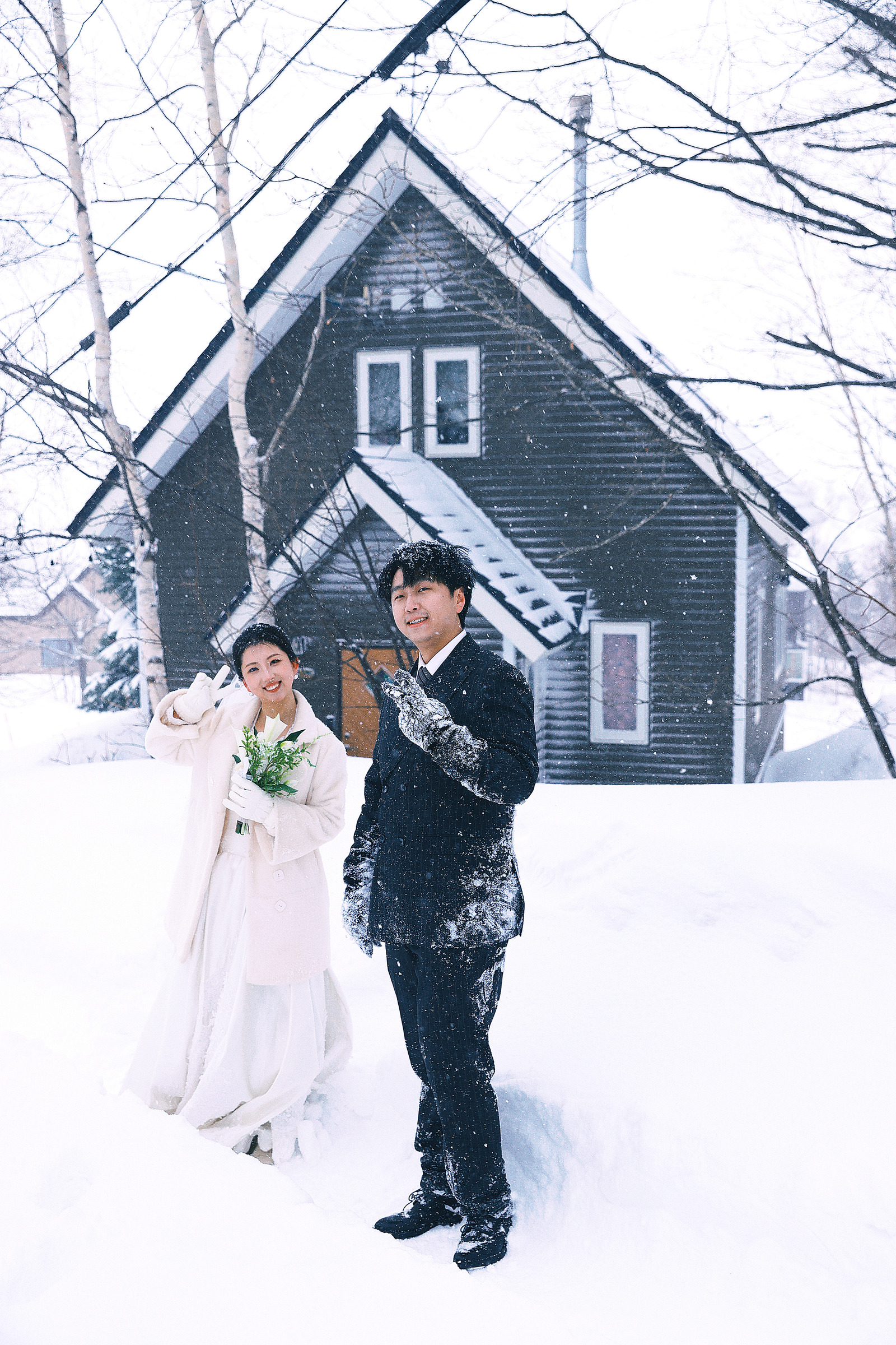黑色木屋前站在雪中的两个人